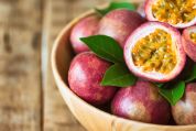 Eine Holzschale mit Passionsfrüchten - teils aufgeschnitten - und deren Blätter.  Eine Holzschale mit Passionsfrüchten - teils aufgeschnitten - und deren Blätter.